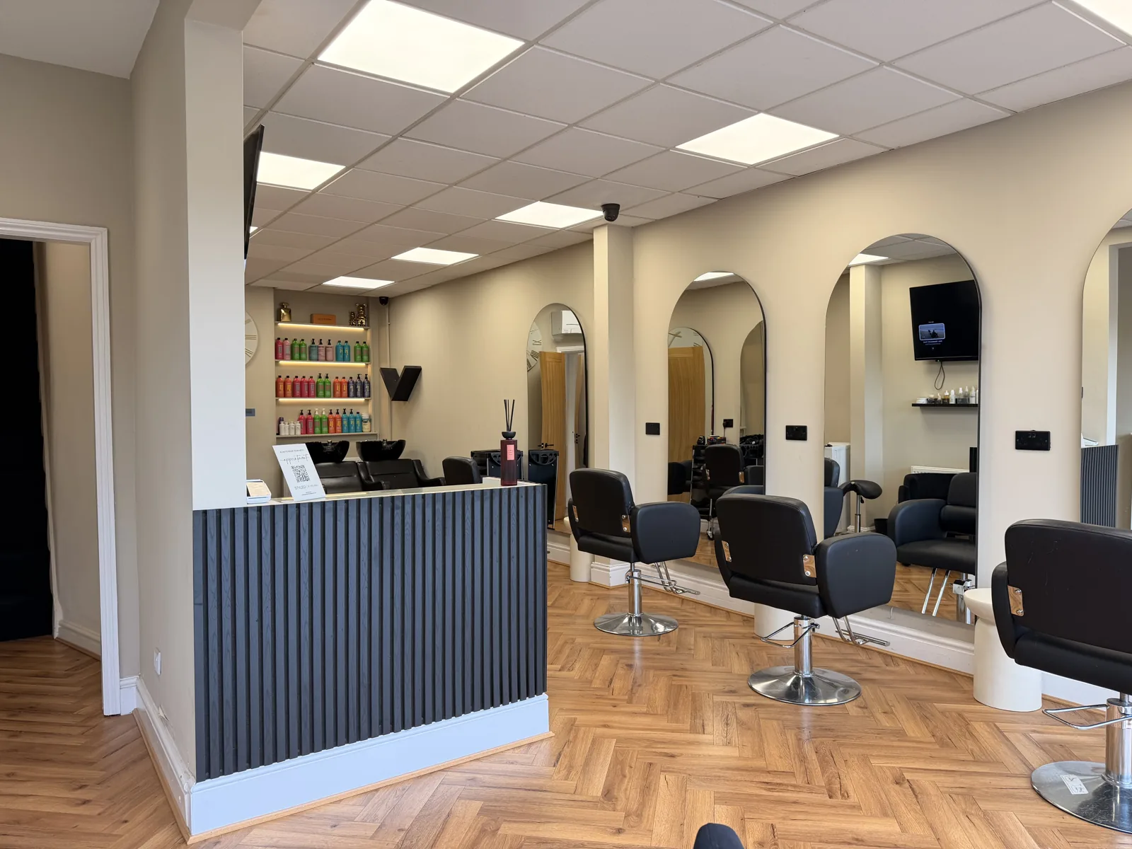 View into STYLED with reception desk, styling chairs and mirrors